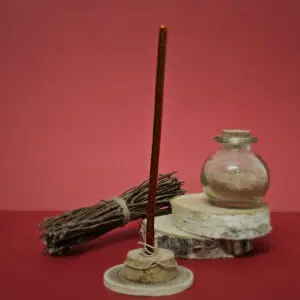 Mini bougie rouge bordeaux en cire d'abeille naturelle posée sur une surface lisse, émettant une petite flamme douce, illustrant son utilisation dans un rituel magique apaisant.