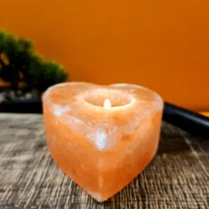 Image d'un bougeoir en forme de cœur fait de cristal de sel de l'Himalaya. Il diffuse une lumière douce et chaleureuse, parfait pour créer une ambiance apaisante et élégante dans n'importe quelle pièce. Idéal pour la méditation, la relaxation, et la décoration intérieure.