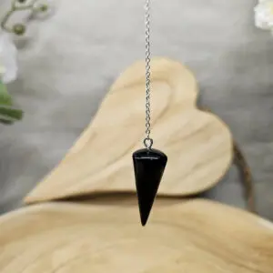 Pendule en obsidienne noire naturelle pour la radiesthésie, utilisé pour la protection énergétique et l'ancrage spirituel, avec une chaîne en métal argenté.