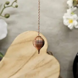 Pendule boule striée en cuivre avec chaîne, conçu pour la radiesthésie et les recherches précises sur cartes et plans. Compact, précis et réactif.