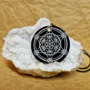 La médaille Le Talisman Métatron posée sur un cristal blanc montre le Cube de Métatron gravé au centre.