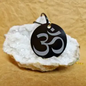 La médaille Le Talisman Ôm posée sur un cristal blanc montre le symbole Ôm gravé en grand.