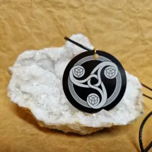 La médaille Le Talisman de l’Énergie Triskel posée sur un cristal blanc montre un Triskel celtique gravé en blanc.