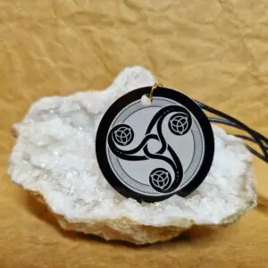 La médaille Le Talisman de l’Énergie Triskel posée sur un cristal blanc montre un Triskel celtique gravé en blanc.