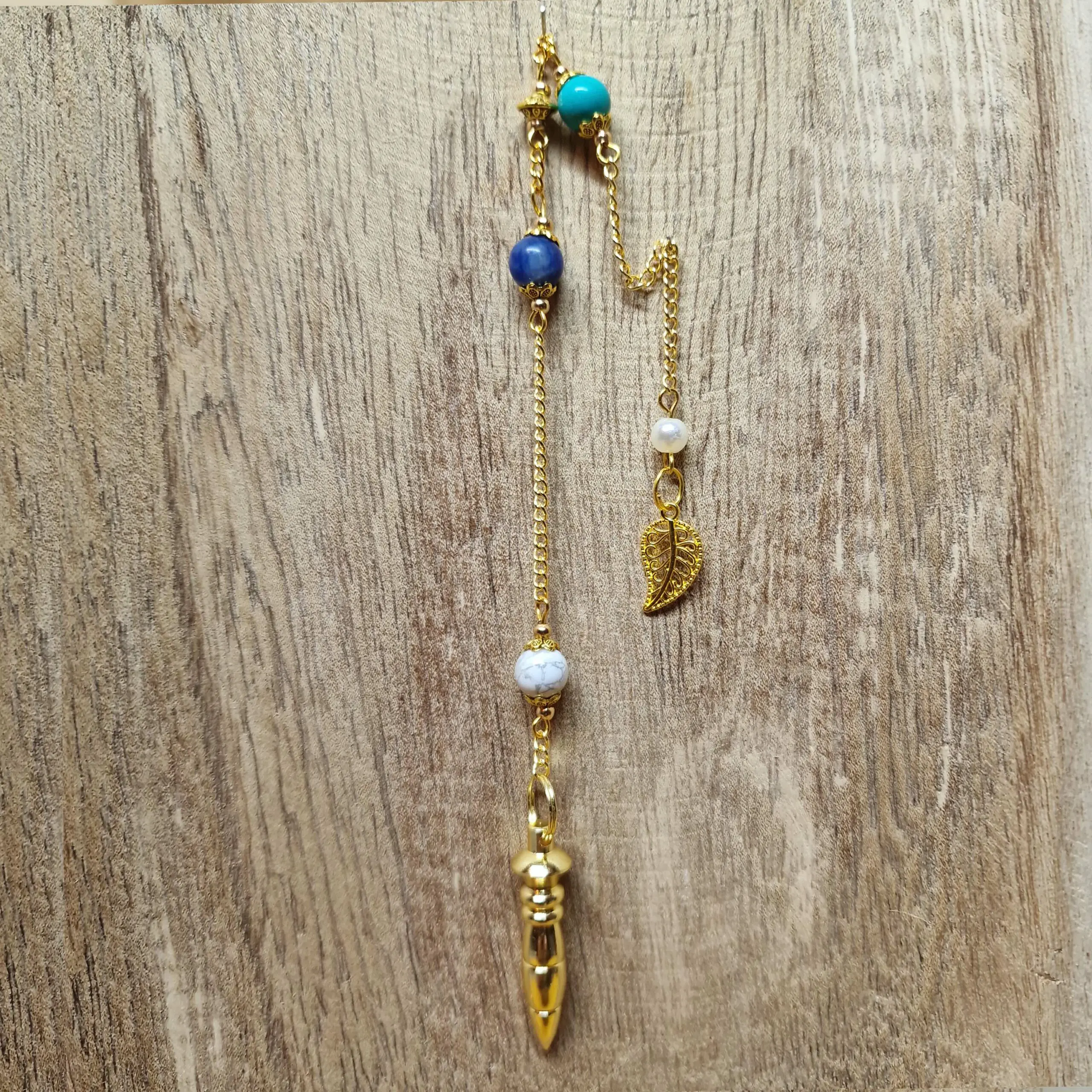 Image du Pendule Chemin de Vie 5 composé de Turquoise, de Sodalite et de Howlite pour soutenir la liberté intérieure, la clarté mentale et l’apaisement.