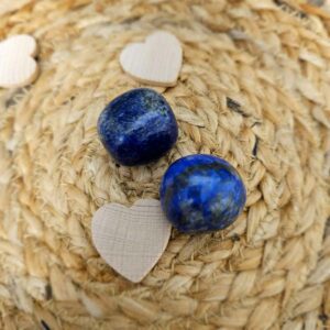 Pierre de lapis-lazuli de couleur bleue intense, mesurant entre 2 et 3 cm. Cette pierre est souvent utilisée pour fortifier la parole, la communication et le chant, ainsi que pour stimuler l'intuition et la clairvoyance. Placée sur une surface blanche, elle révèle ses nuances profondes et ses petites inclusions dorées.