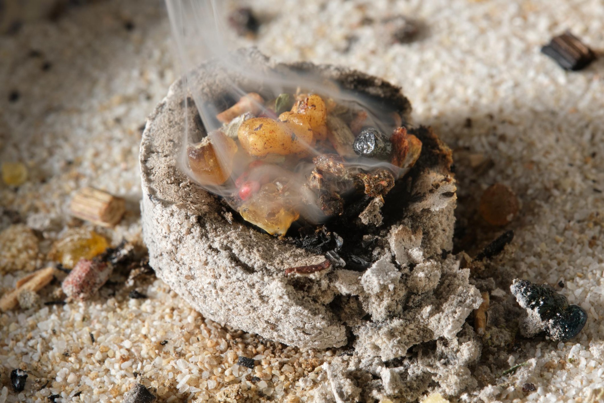 Grains d’encens résine fondant sur un charbon ardent avec fumée parfumée lors de la combustion de l’encens en grains.