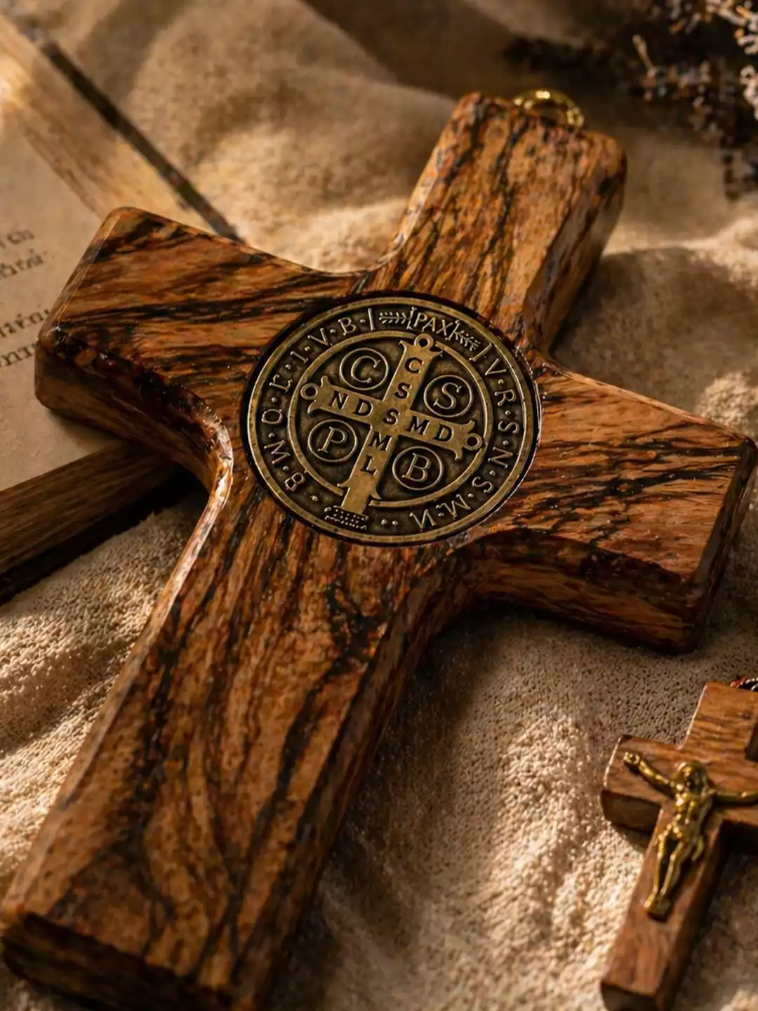 Croix de Saint Benoît en bois d’olivier sombre avec médaille en bronze patiné, chapelet de bois et missel ancien ouvert.