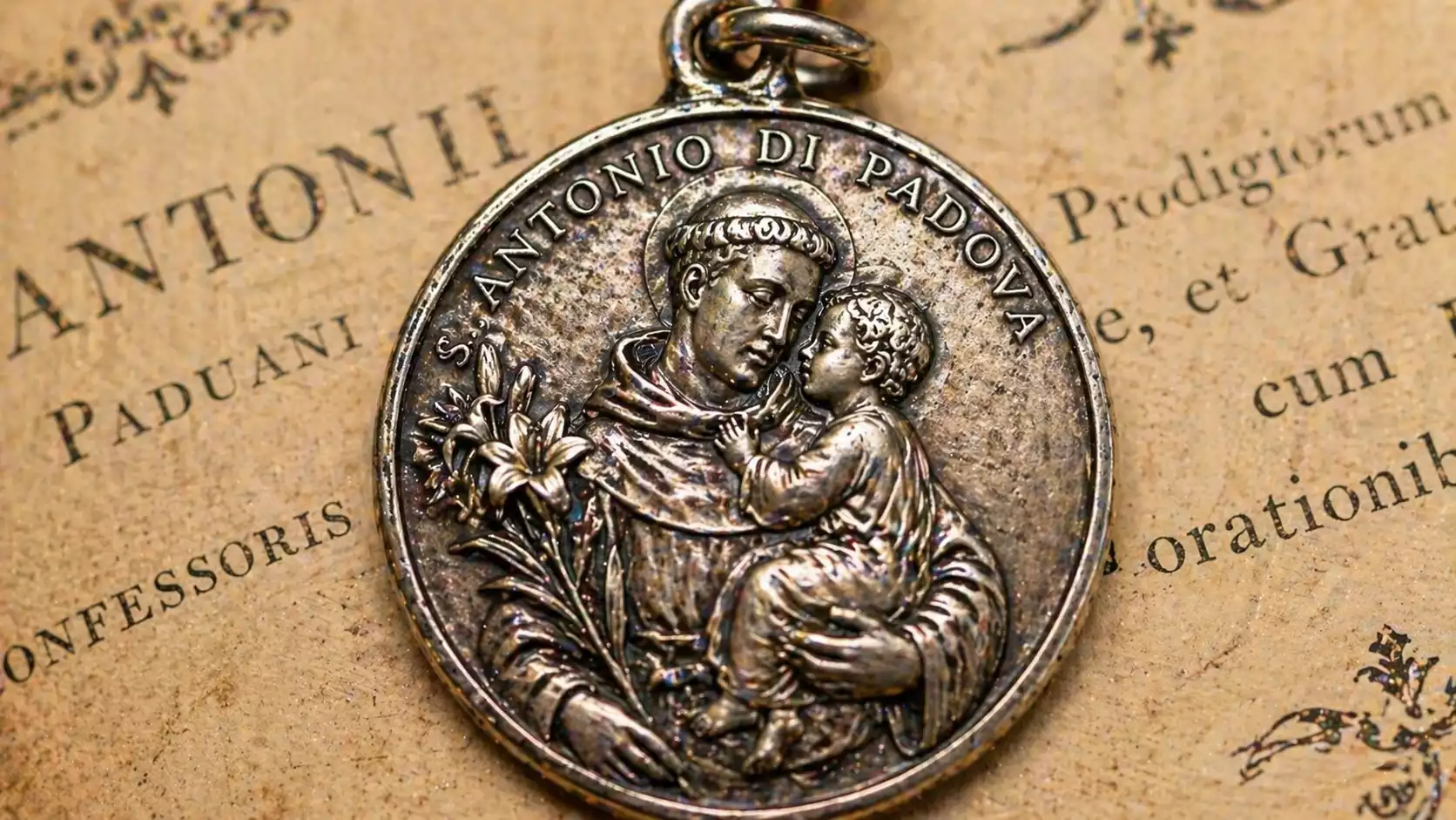 Détail de médaille Saint Antoine avec Enfant Jésus et lys Détail macro d’une médaille de Saint Antoine en argent avec l’Enfant Jésus dans les bras du saint et le lys de pureté.
