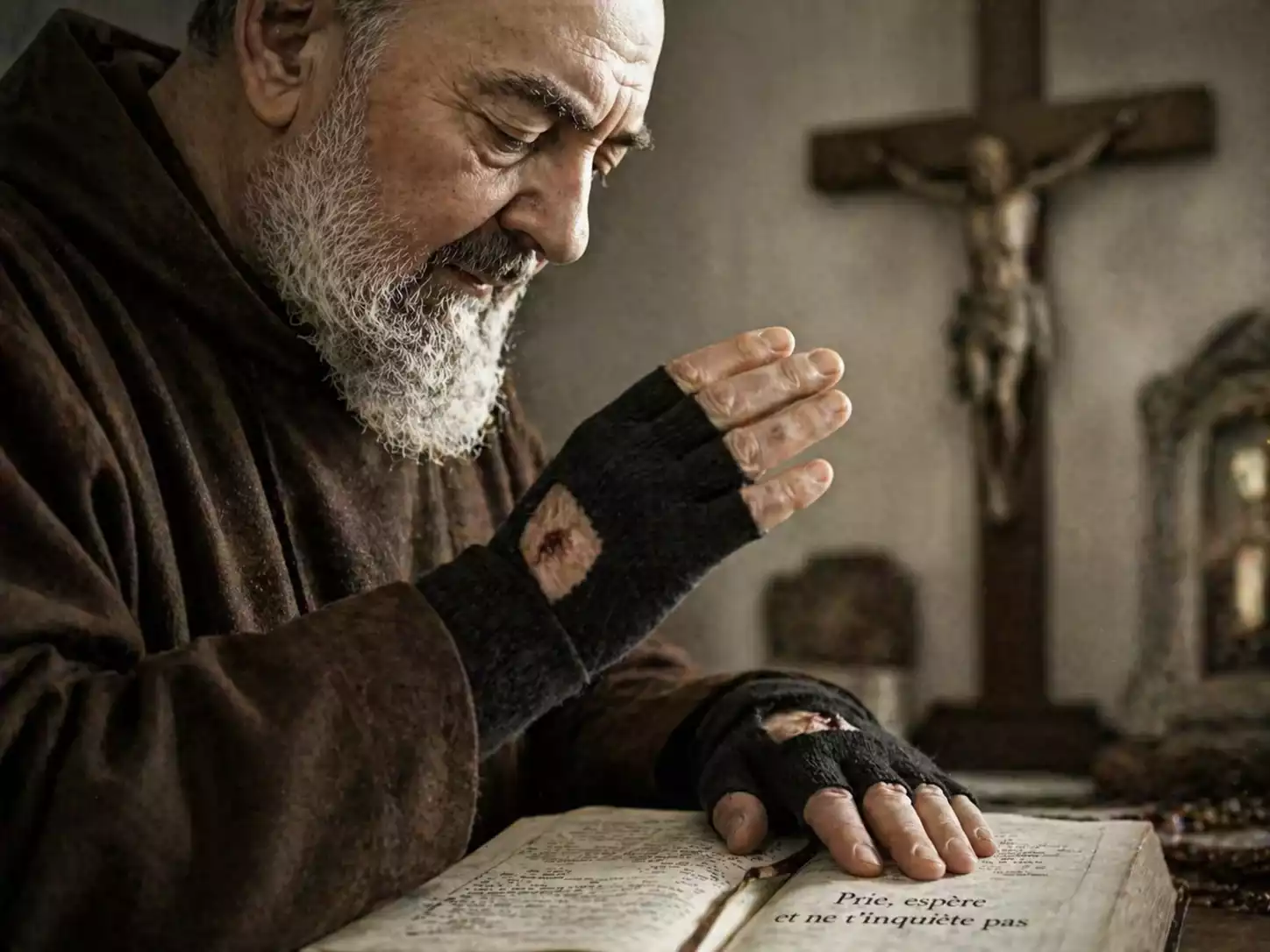 Mains de Padre Pio avec mitaines noires couvrant les stigmates, posées sur un livre de prières ouvert devant un crucifix.